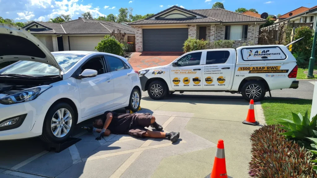 inspector doing a pre purchase inspection by looking under the car